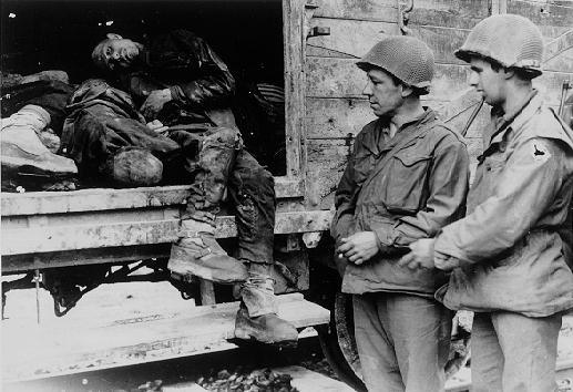 American soldiers pose beside the bodies of SS soldiers killed during the liberation of Dachau